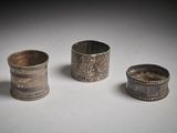 trois pièces d'argenterie anciennes sont posées sur une surface blanche