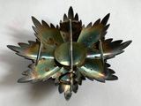 une broche en forme de fleur en métal posée sur une surface blanche