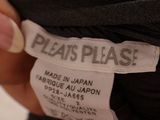 someone is holding a black shirt with a white label on it