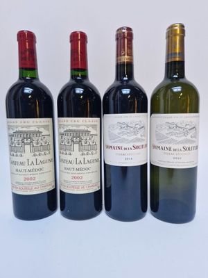 quatre bouteilles de vin sont alignées sur une surface blanche