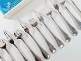 several forks and spoons are lined up next to a box of toothpaste