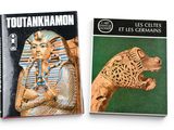 two books on a white background with a picture of a statue of a lion and an egyptian mask