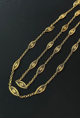 a gold necklace with three chains and a pendant with a leaf design
