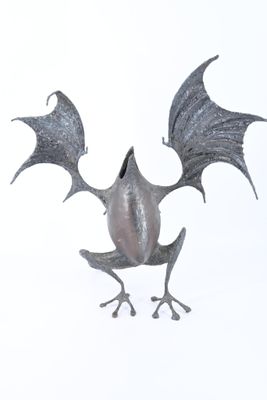 une statue en métal représentant une chauve-souris aux ailes déployées