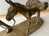 a bronze statue of a donkey on a wooden stand