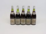 quatre bouteilles de vin sont alignées sur une surface blanche