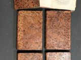 four pieces of brick sitting on a table next to an open book