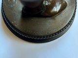 a bronze statue of a shoe on top of a coin