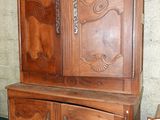 une armoire en bois munie d'une porte, devant laquelle se trouve une chaise