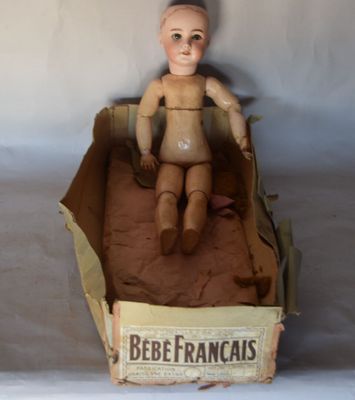 une poupée assise dans une boîte en carton posée sur une table
