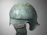 a close up of a bronze helmet on a gray background