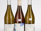 trois bouteilles de vin blanc posées les unes à côté des autres sur une table