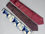 three ties with different designs on them sitting on a white surface