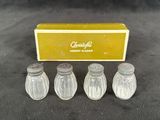 four glass salt and pepper shakers in a box on a table
