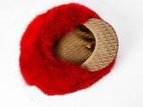the red fur hat is laying on top of a white surface
