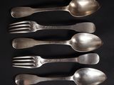 cinq cuillères en argent et une fourchette sur un fond noir