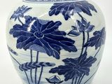 a blue and white vase with flowers and leaves on it