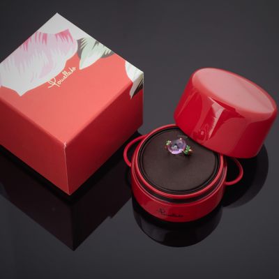 une boîte rouge contenant un anneau, posée sur une surface noire