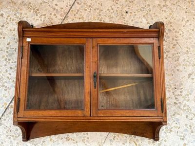 a small wooden cabinet with glass doors on the wall