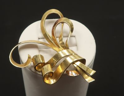 a gold bow brooch sitting on a white cup