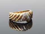 a close up of a gold and diamond ring on a reflective surface