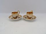 two cups and saucers are sitting on a white surface