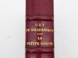 an old book with a red cover sitting on top of a table