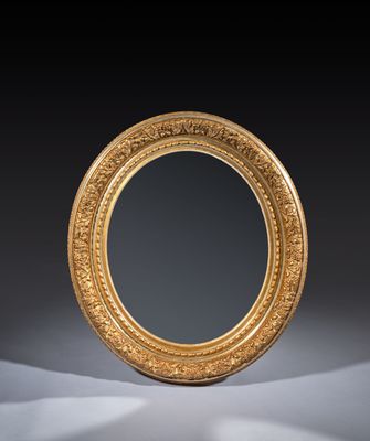 an oval mirror with a gold frame on a black background