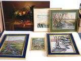 quatre tableaux posés sur une table, avec un vase rempli de fruits en arrière-plan