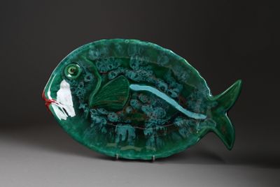une assiette verte sur laquelle est posé un poisson, posée sur une table
