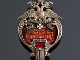 an image of a silver and red broochle with two birds on it
