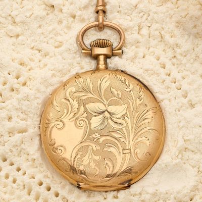 une vieille montre de poche en or, avec une chaîne suspendue sur le côté
