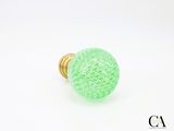 un gros plan d'un bouton en verre vert sur fond blanc