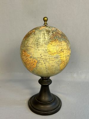 un petit globe posé sur un socle, sur une surface blanche