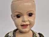 a close up of a doll wearing a dress and smiling