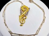 a gold necklace with a dragon on it on a white plate