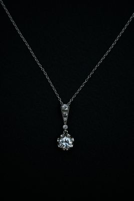 a white gold pendant with a diamond set in the center on a black background