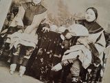 an old photo of two women sitting on a bench with a baby