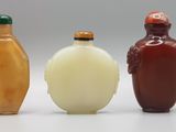 trois flacons à tabac en verre posés les uns à côté des autres sur une surface blanche