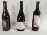 three bottles of wine are lined up on a white surface