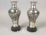 une paire de vases en argent posés sur un socle en bois