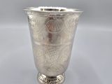 an antique silver cup with a floral design on the rim