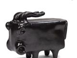 a small black cow statue on a white surface