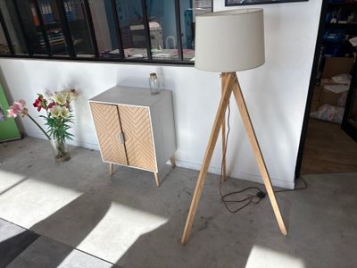 une lampe posée sur un trépied à côté d'une armoire