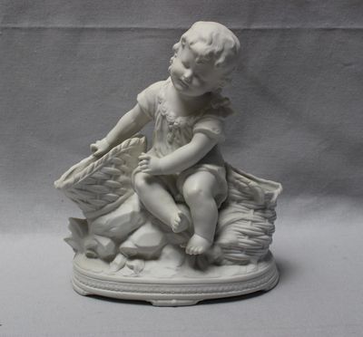 une petite statue représentant un garçon assis sur un rocher