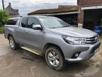 La Toyota Hilux est garée devant un immeuble en briques