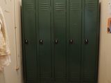 a green locker in a bathroom with a towel hanging on the wall