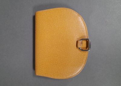 yellow leather wallet with a metal buckle on a gray surface