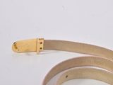 a close up of a belt with a gold buckle on a white surface