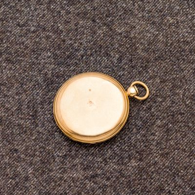une image représentant une montre de poche en or posée sur un tapis bleu